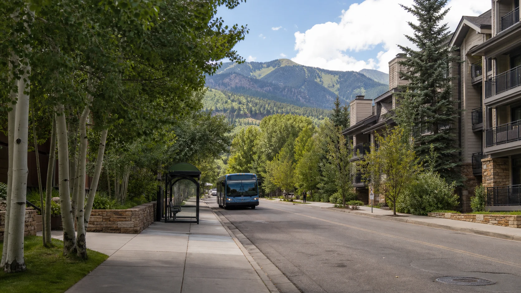 An Aspen residential street with a bus stop, local bus and mountains beyond