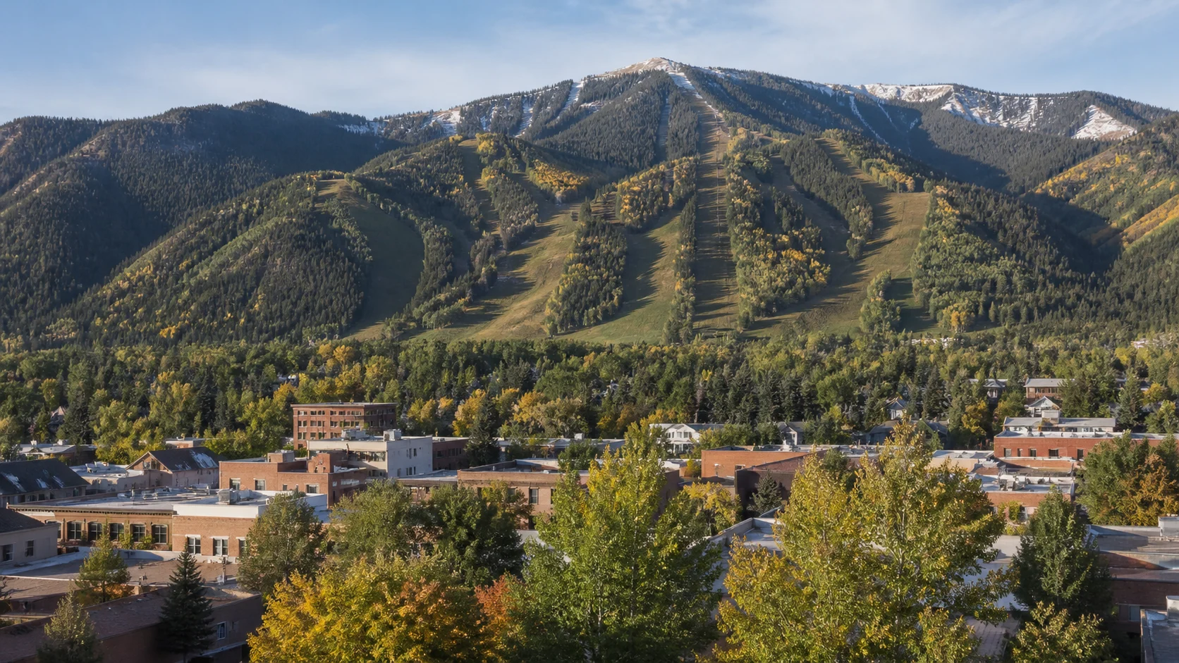 Aspen town buildings and mature trees below Aspen Mountain in early autumn