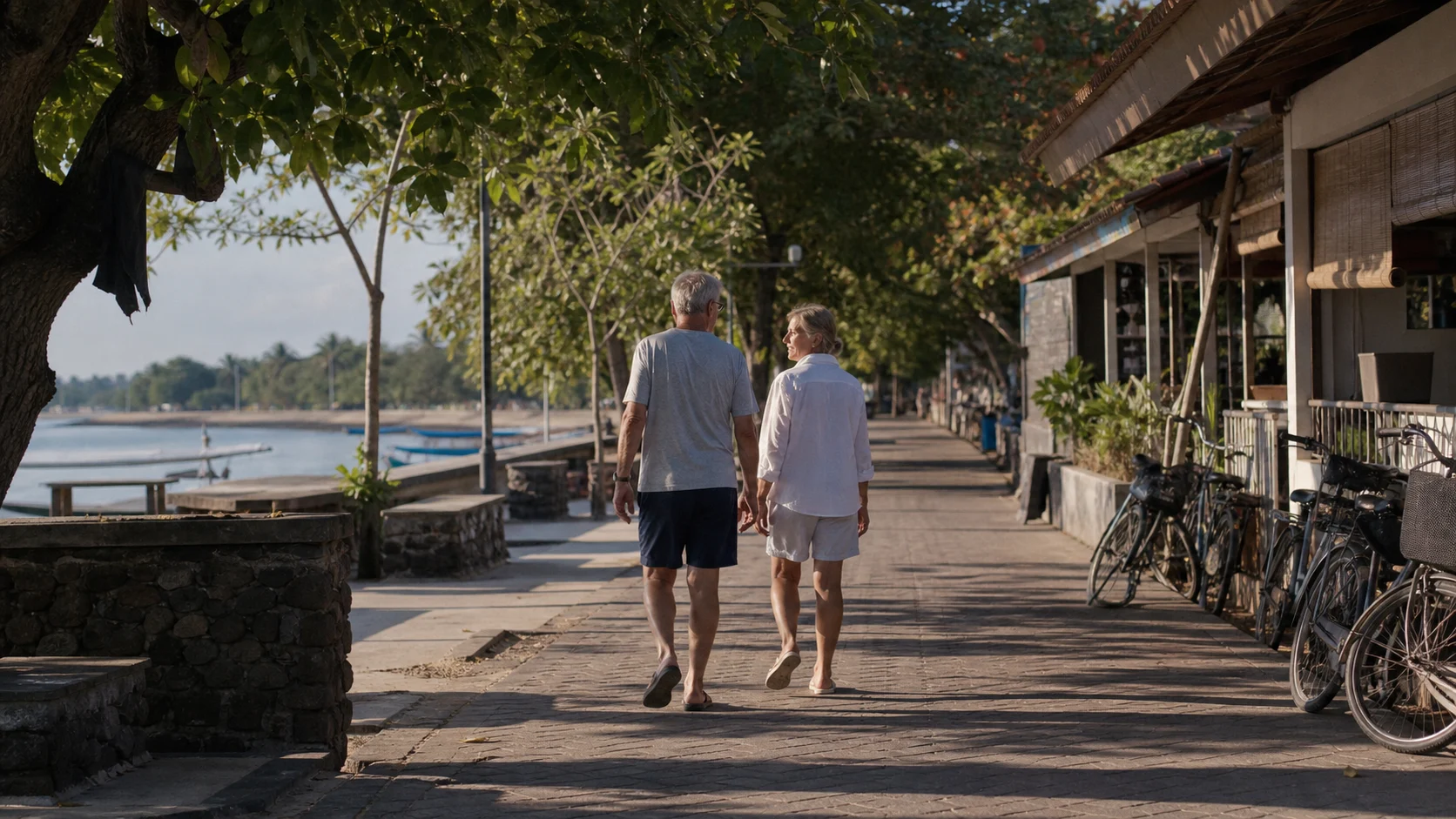 Older couple walking along Sanur promenade in warm morning light