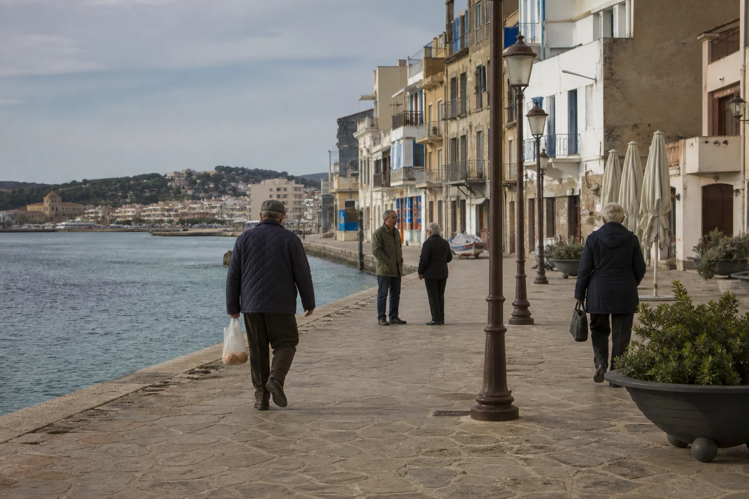 Residents walking beside a lived-in Costa Brava waterfront outside peak summer