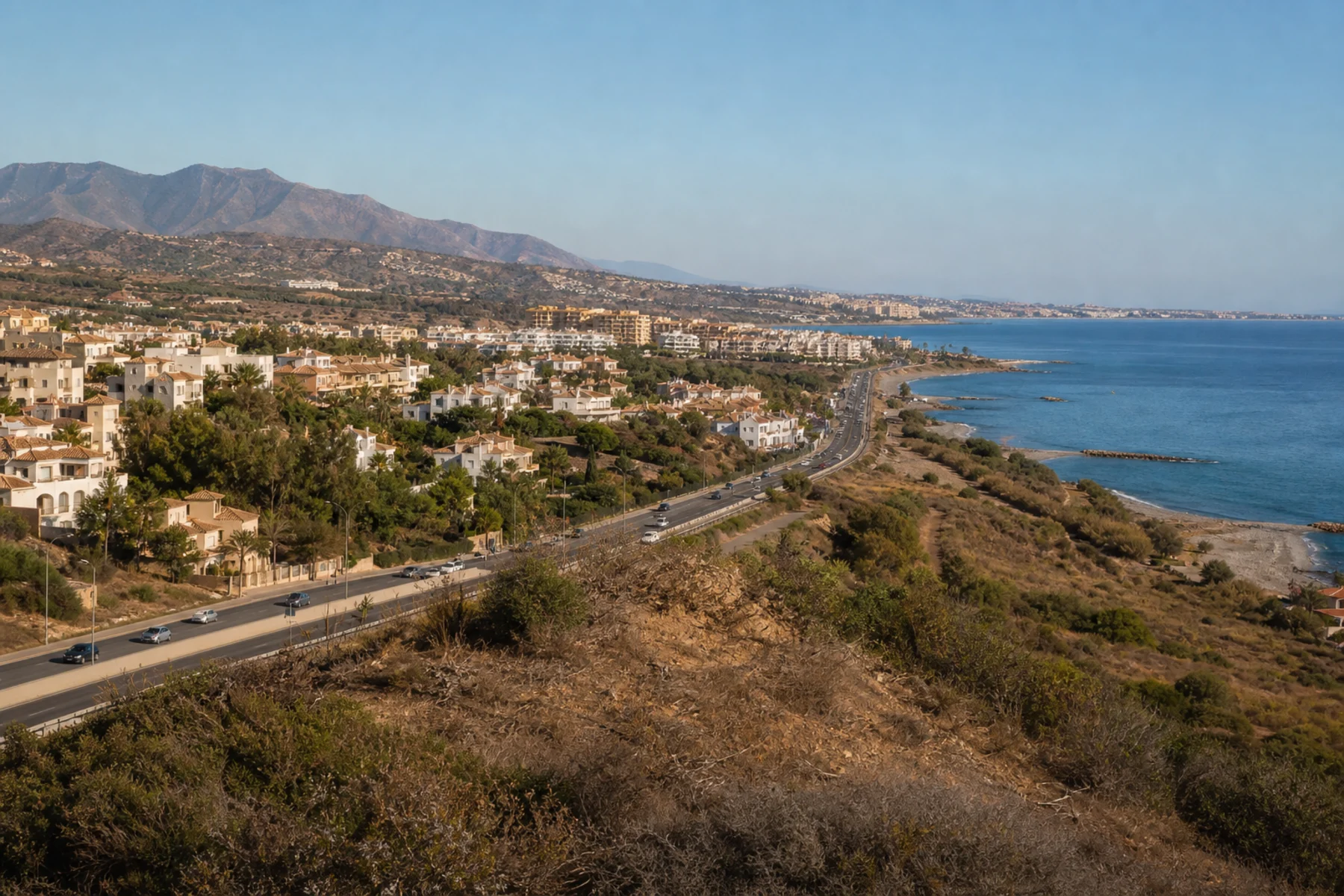 Homes, the coastal road and dry hills west of Málaga