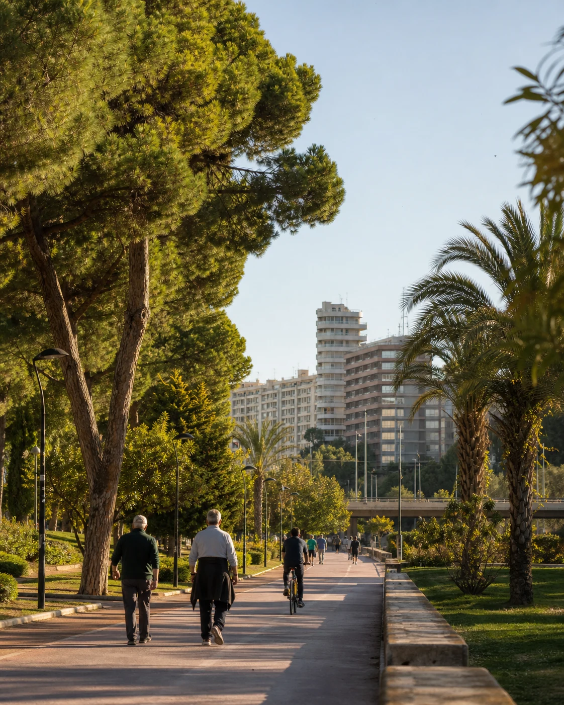 Older residents and cyclists using Valencia's green Turia Gardens corridor in warm morning light