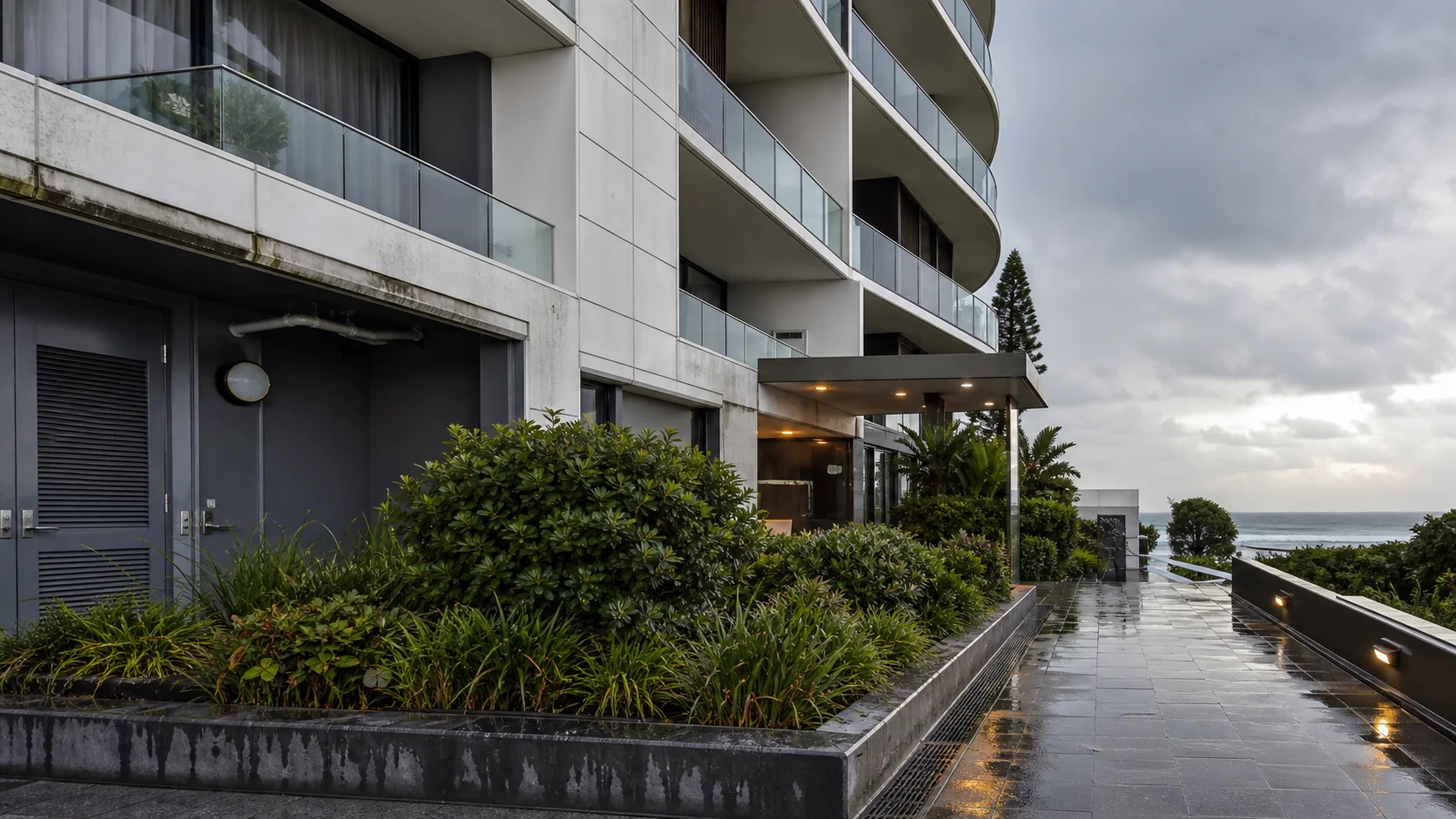 Contemporary Australian coastal apartment building after rain with balconies and drainage visible