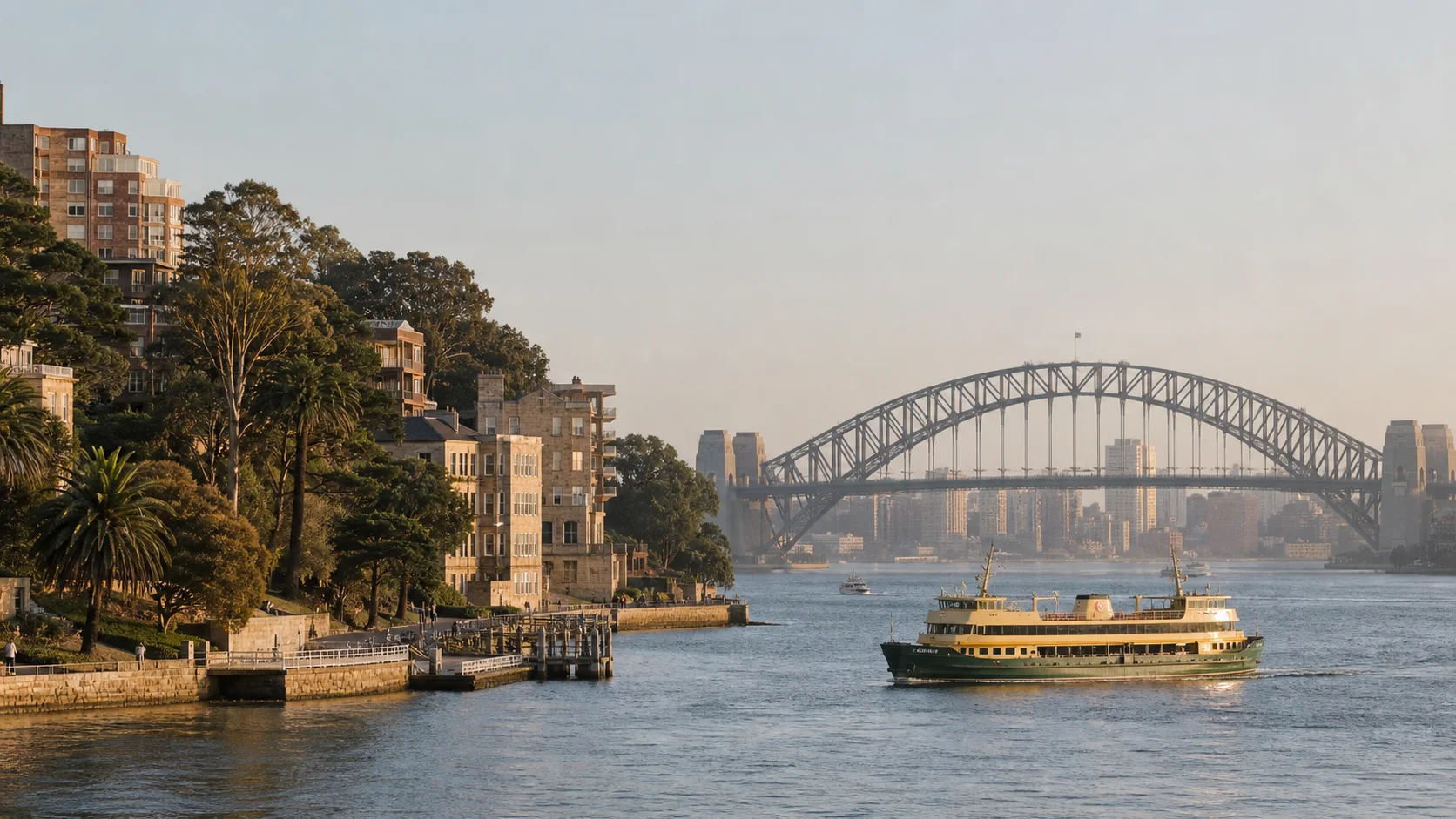 Sydney Harbour ferry passing residential sandstone buildings and the Harbour Bridge